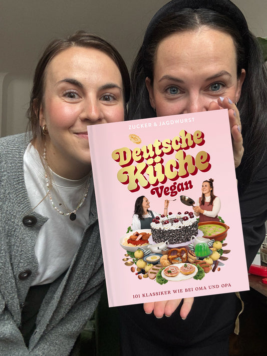 Die Gründerinnen von Zucker & Jagdwurst, Isa & Julia, halten das Kochbuch “Deutsche Küche Vegan” in der Hand